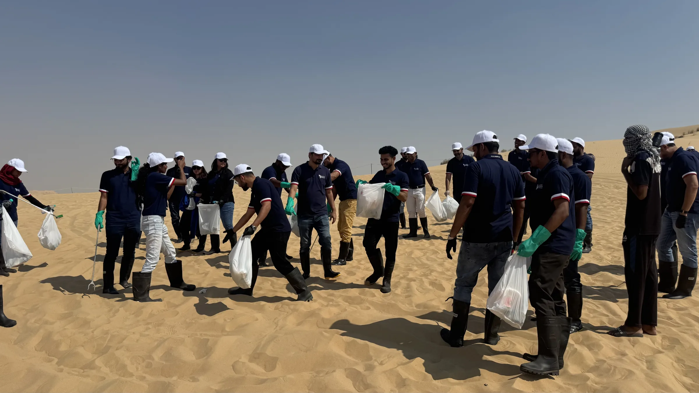 Dolphin Group volunteers collecting bags of waste together in the desert